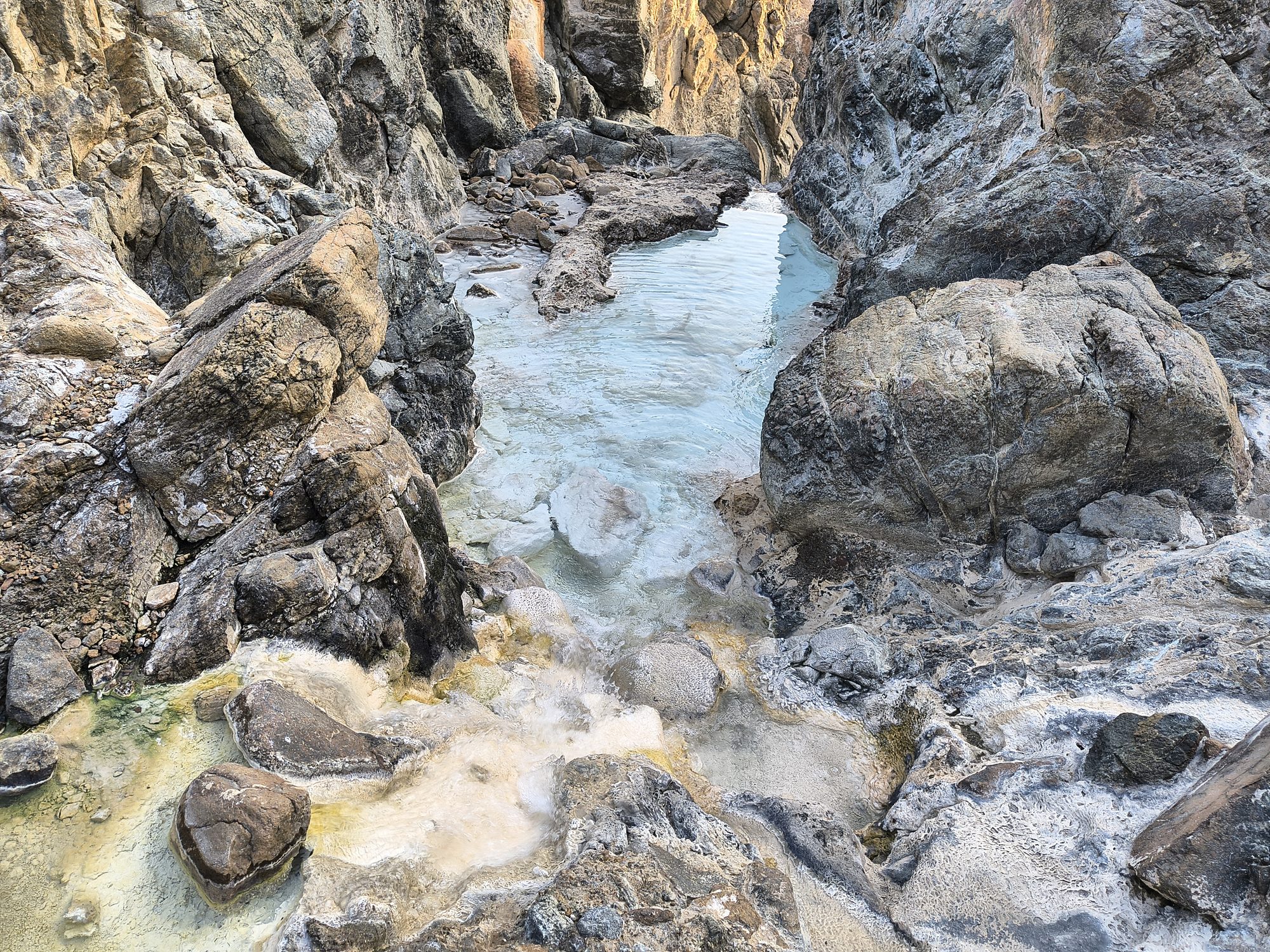 White carbonate crust in a stream bed between serpentinite boulders